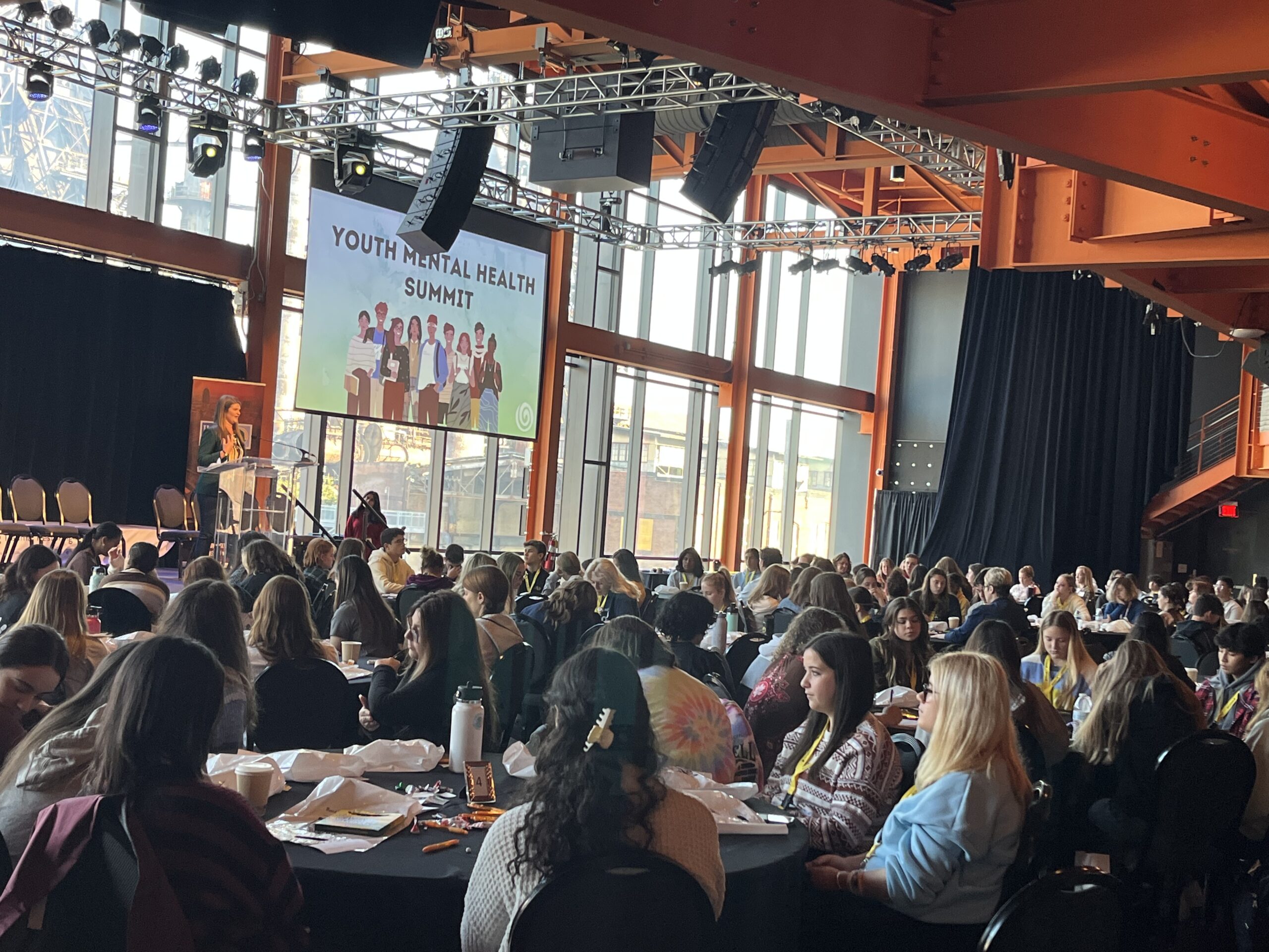 Students sitting with Youth Mental Health Summit signage