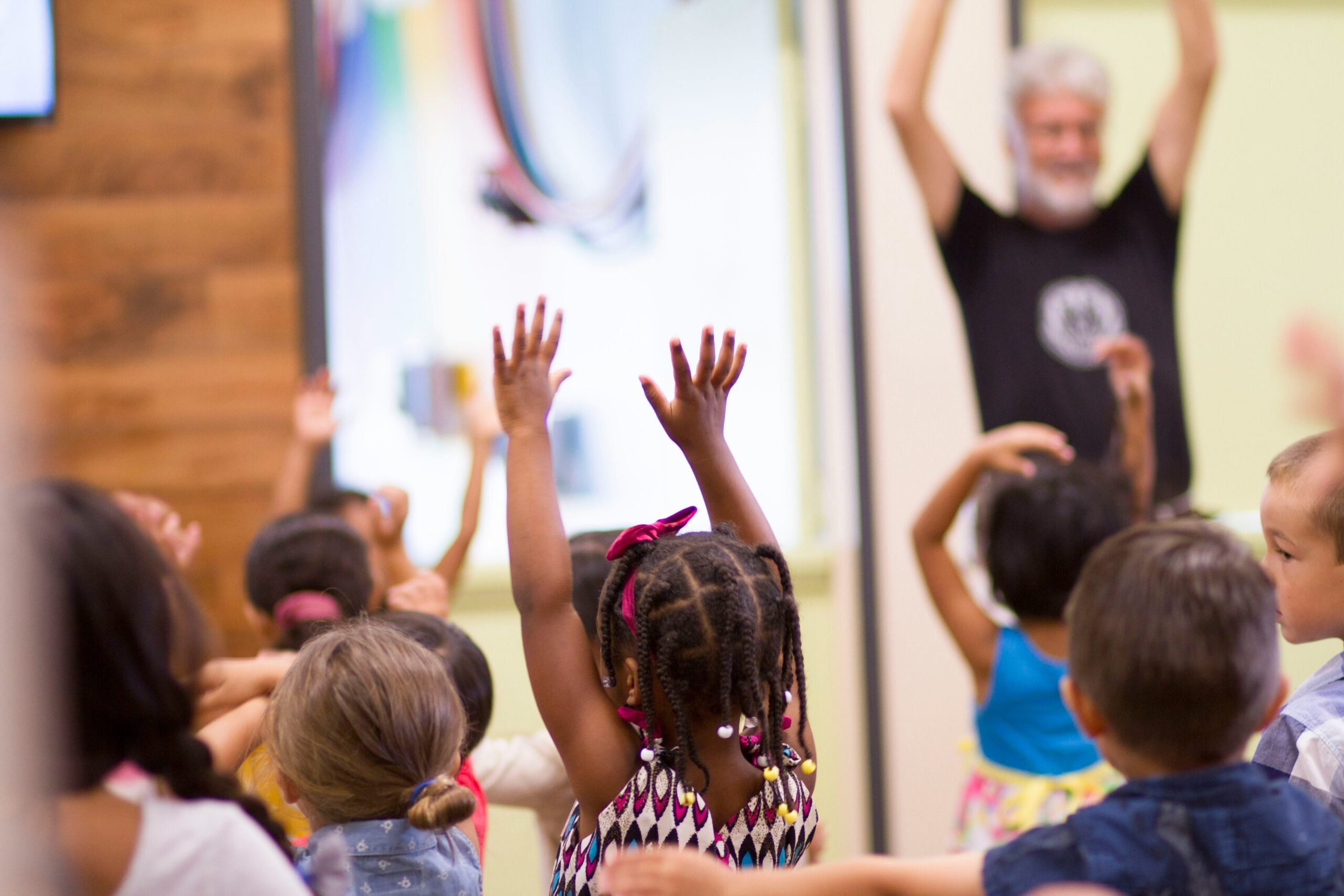 children raising their hands and happy in a school